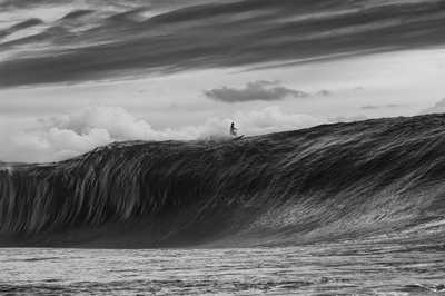 A solo person at the top of a huge wave