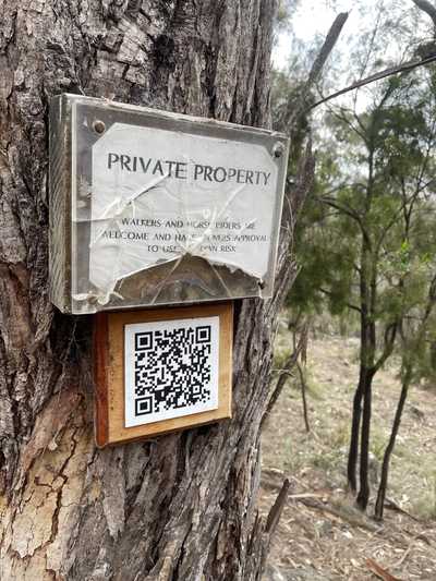 Asign and a QR code on the side of a tree