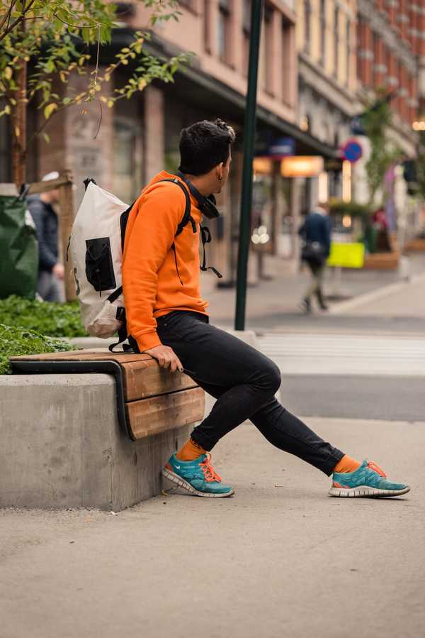 A man sitting on a wooden bench, on top of concrete