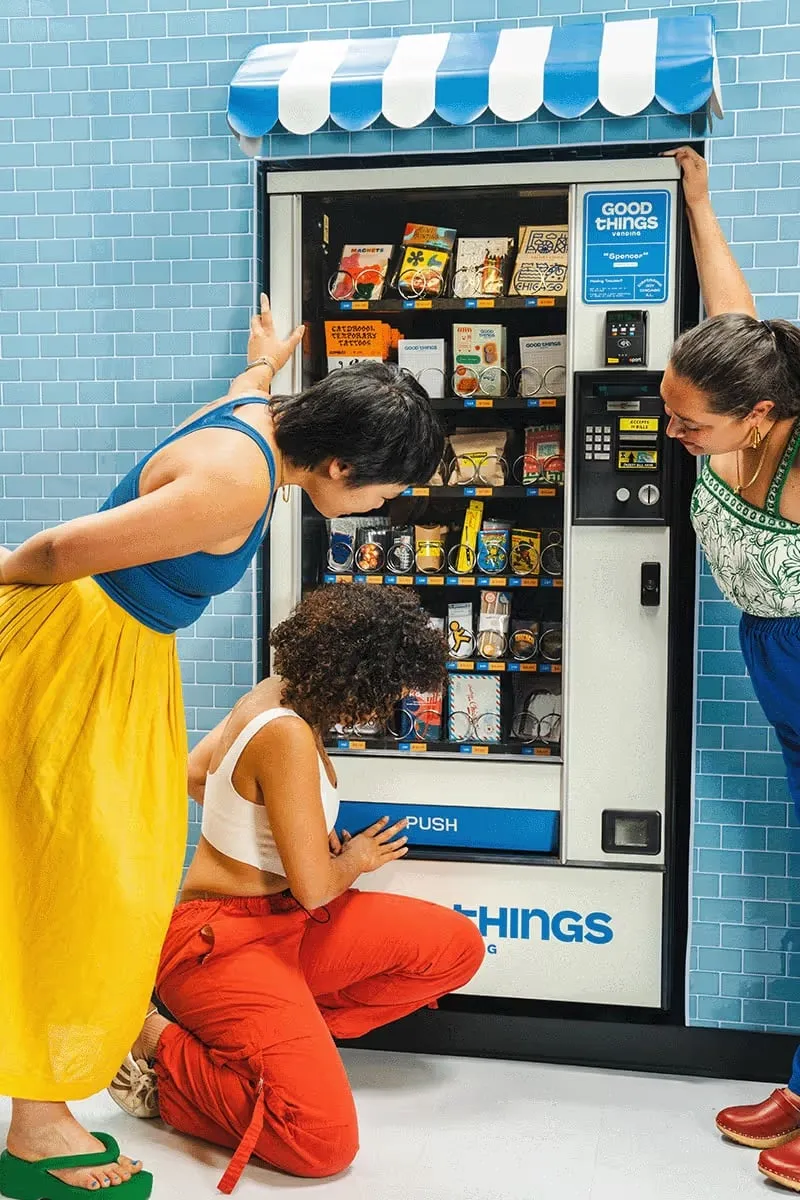 Photo of 3 people surrounding a vending machine filled with art